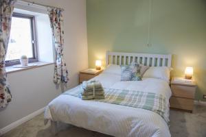a bedroom with a bed with two lamps and a window at Little Thornsett in Buxton