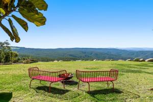 two red benches sitting in a grassy field at The Quince Cottage - 2 Bedrooms in Ravensbourne