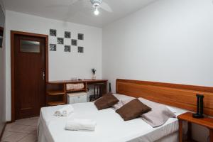 1 dormitorio con 1 cama con sábanas blancas y almohadas marrones en Ilha Náutica, en Florianópolis 43 fotos más
