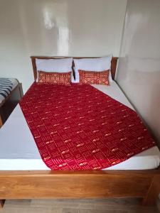 Campement Le Canoë في Oussouye: سرير مع لحاف احمر ووسادتين