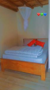 Campement Le Canoë في Oussouye: سرير صغير مع ملاءات زرقاء ووسائد حمراء +5 صور
