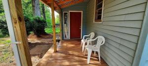 due sedie bianche su un portico con una porta rossa di The Blue Cabin a Stuart