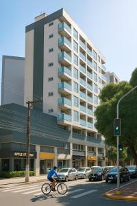Un uomo che va in bicicletta davanti a un palazzo di Flat Praia do Canto Collection View a Vitória