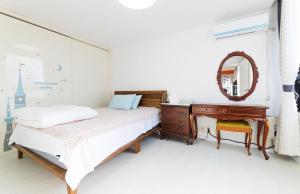 a bedroom with a bed and a dresser and a mirror at Paju Gallery Café Pension Soon in Paju