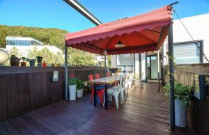 a deck with a table and chairs and an umbrella at Paju Gallery Café Pension Soon in Paju