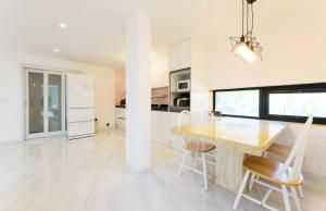 a white kitchen with a wooden table and chairs at Paju Gallery Café Pension Soon in Paju +3 photos