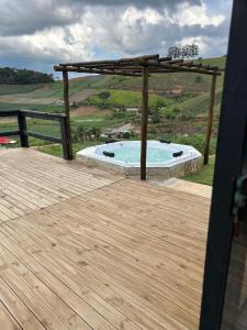 a swimming pool with a pergola and a wooden deck at Chalé do Campo in Sumidouro