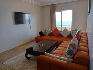 a living room with an orange couch and a television at Appart 3p vue sur mer in Rabat