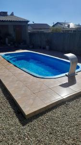 een blauw zwembad met een bankje naast een hek bij Casa Ana y Ángelo in Pântano Grande