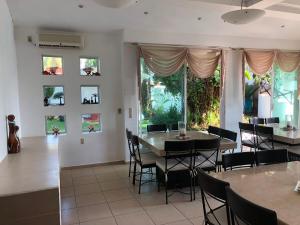 Un comedor con mesas y sillas y ventanas. en Quinta Charito, Amplia Villa Familiar junto al Mar, en Los Cocos