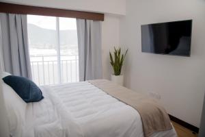 a bedroom with a bed with a television and a window at Glam - Apartamento exclusivo cerca del Consulado de México y centros comerciales in Quetzaltenango