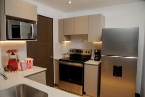 a kitchen with a stove and a stainless steel refrigerator at Glam - Apartamento exclusivo cerca del Consulado de México y centros comerciales in Quetzaltenango