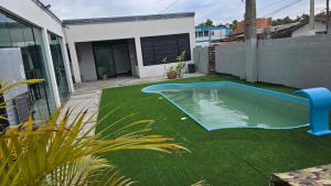a backyard with a swimming pool and green grass at Karina Saraiva in Palhoça