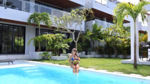 a woman in a bikini sitting in a swimming pool at Gandum Villa Complex - Luxury Boutique Stay Uluwatu in Uluwatu