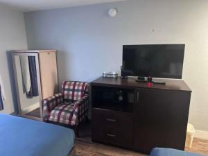 a bedroom with a tv and a chair and a dresser at Ocean Paradise Hotel & Resort in Ocean Shores