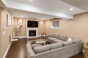 Executive 2BR Lower Suite Private & Spacious Close to USA Border في ويندسور: غرفة معيشة مع أريكة ومدفأة