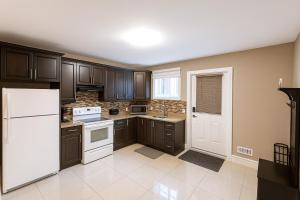 a kitchen with brown cabinets and a white refrigerator at Executive 2BR Lower Suite Private & Spacious Close to USA Border in Windsor