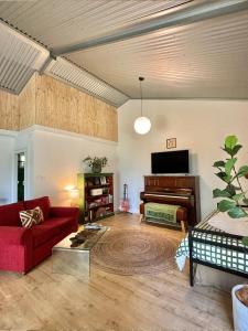 Coral Fern Farm Stay في Mongans Bridge: غرفة معيشة مع أريكة حمراء وبيانو +22 صورة
