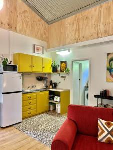 Coral Fern Farm Stay في Mongans Bridge: مطبخ مع خزائن صفراء واريكة حمراء