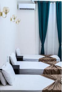 two beds in a hotel room with blue curtains at The Egyptian apartment in Cairo