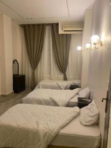 a hotel room with three beds and a window at The Egyptian apartment in Cairo