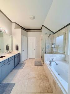 een grote badkamer met een bad en een wastafel bij Spacious Centrally Located with Heated Pool in Frisco