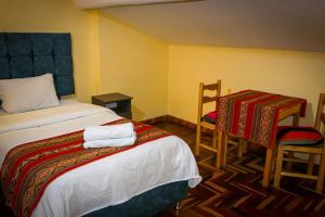 Un dormitorio con una cama y una mesa y sillas. en hawka pacha cusqueña, en Cusco