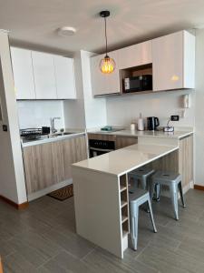 a kitchen with white cabinets and a counter with stools at Departamento frente a la playa in Iquique