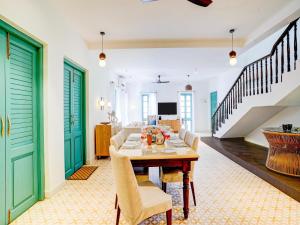 Valencia By DanCenter - 3 Bhk Villa in Siolim في Camorlim: غرفة طعام بأبواب خضراء وطاولة