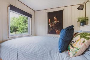 ein Schlafzimmer mit einem Bett und ein Gemälde einer Frau in der Unterkunft The Hideaway at Hidden Wood Glamping in Corsley