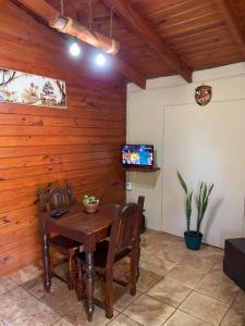 Un comedor con mesa y sillas y un televisor. en Cabañas Canaan, en La Cumbre
