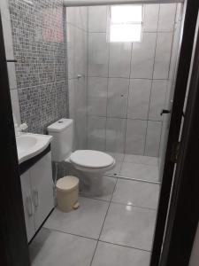 a white bathroom with a toilet and a shower at Apto com terraço coberto in Arroio do Sal