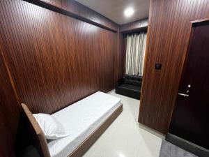 a small room with a bed and a wooden wall at K V URA Kohima in Kohīma