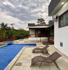 a house with a swimming pool and two chairs next to it at K&S Kanto Sereno in Pirenópolis +29 photos