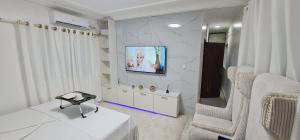 Ein weißes Zimmer mit einem Fernseher und zwei Stühlen in der Unterkunft O'sena in Cotonou