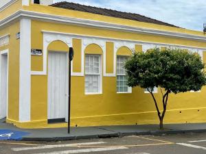 a yellow building with a tree in front of it at Casarão Centenário in Passos