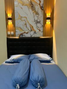 a bed with blue pillows in a bedroom with a wall at Tentrem Madani in Yogyakarta