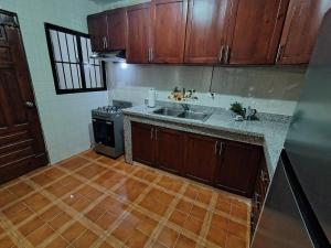 a kitchen with wooden cabinets and a sink and a stove at Comfortable and quiet double room in Santo Domingo