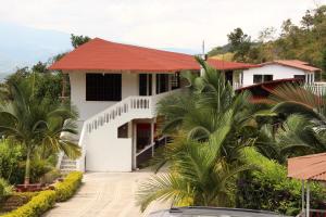 a white house with a red roof and palm trees at Hotel Campestre VillaMaria in Vergara