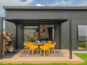 a patio with a table and yellow chairs at Sun and Sea Sanctuary - Whitianga Holiday Home in Whitianga