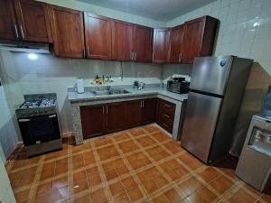 a kitchen with wooden cabinets and a stainless steel refrigerator at Comfortable and quiet double room in Santo Domingo +7 photos