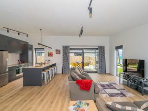 a living room with a couch and a tv and a kitchen at Sun and Sea Sanctuary - Whitianga Holiday Home in Whitianga