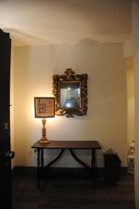 een tafel met een spiegel en een lamp aan een muur bij La Mainolda B&B in Mantova