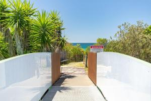a sign on a bridge over a road with palm trees at Beachside 7 in Diamond Beach +9 photos