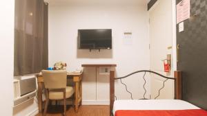 a room with a desk and a television on the wall at RedDoorz at Emperor Manila Boutique Hotel in Manila