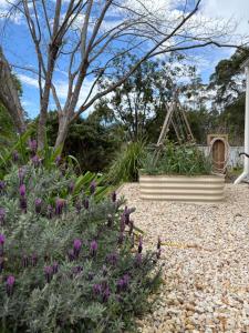 a garden with purple flowers and a swing at The Pottery Shed in Boambee