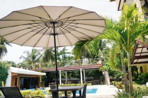 ein großer Sonnenschirm neben einem Pool in der Unterkunft Point 303 Resort in General Luna