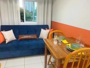 a living room with a blue couch and a wooden table at Studio 731F Conforto no Coração de Foz do Iguaçu in Foz do Iguaçu
