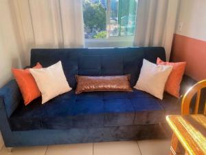 a blue couch with pillows on it in front of a window at Studio 731F Conforto no Coração de Foz do Iguaçu in Foz do Iguaçu