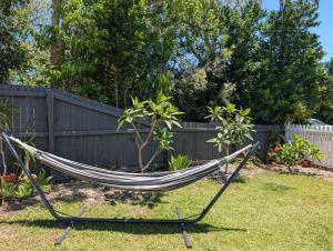 a hammock in a yard next to a fence at Peaceful, Walk to Beach, Bikes, AC, Starlink in Byron Bay